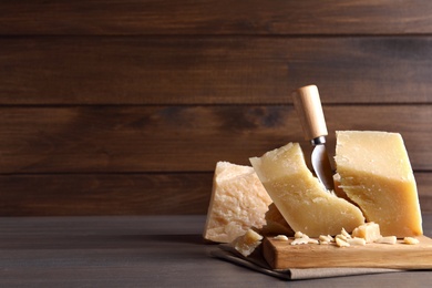 Parmesan cheese with wooden board and knife on table. Space for text Photo of Parmesan cheese with wooden board and knife on table. Space for text