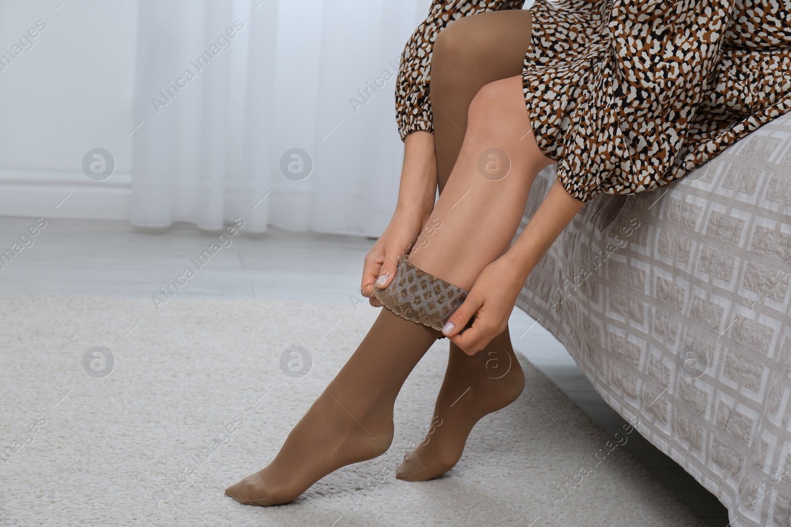 Woman wearing compression tights on bed indoors, closeup Photo of Woman wearing compression tights on bed indoors, closeup