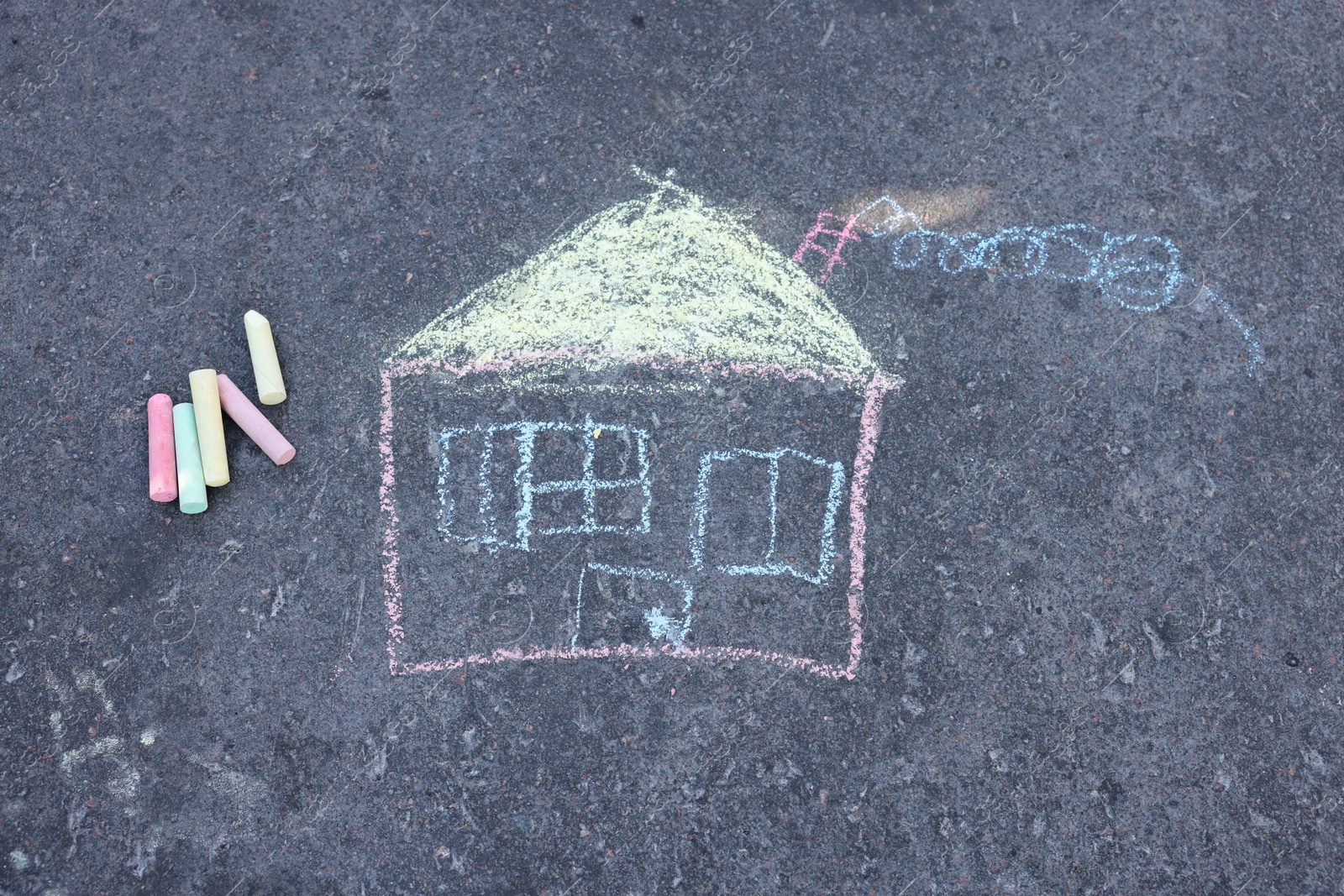 Child's house drawing and pieces of color chalk on asphalt, flat lay Photo of Child's house drawing and pieces of color chalk on asphalt, flat lay