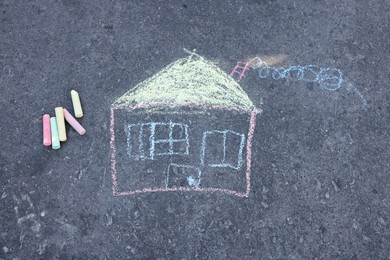 Child's house drawing and pieces of color chalk on asphalt, flat lay Photo of Child's house drawing and pieces of color chalk on asphalt, flat lay