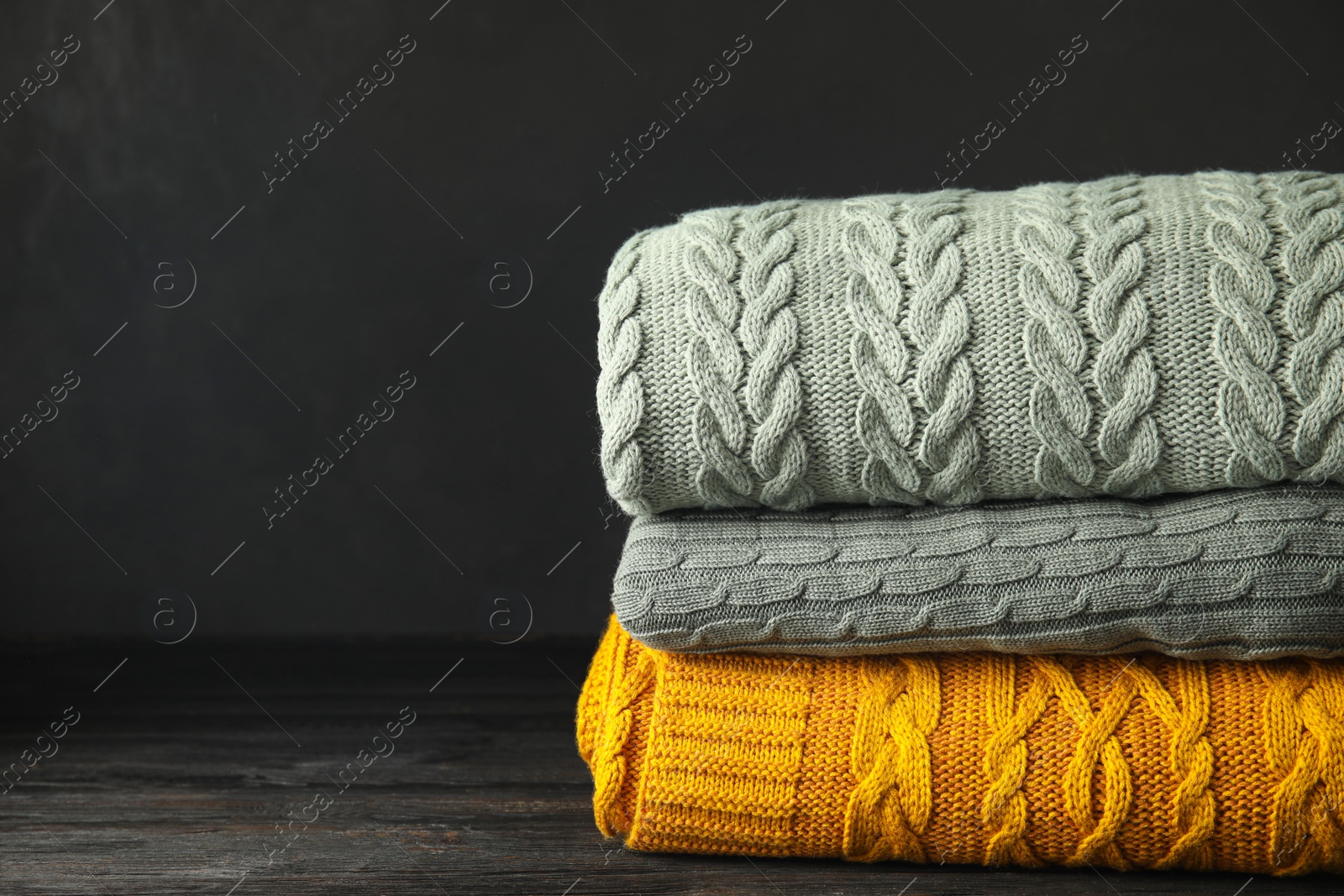 Stack of soft plaids on black wooden table, closeup. Space for text Photo of Stack of soft plaids on black wooden table, closeup. Space for text