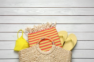 Beach bag with towel, flip flops and swimsuit on white wooden background, flat lay. Space for text Photo of Beach bag with towel, flip flops and swimsuit on white wooden background, flat lay. Space for text