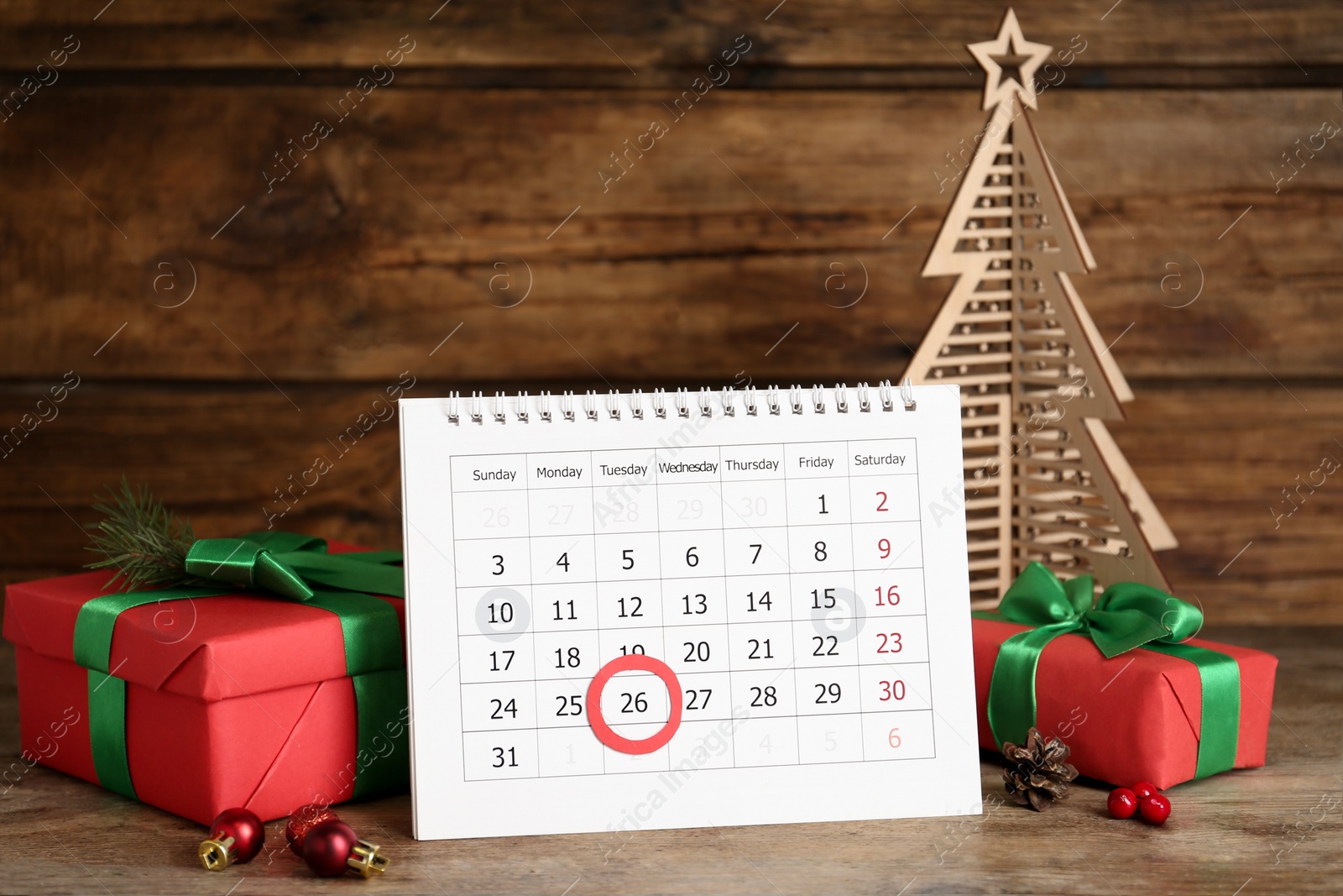 Calendar with marked Boxing Day date near gifts and decorative Christmas tree on wooden table Photo of Calendar with marked Boxing Day date near gifts and decorative Christmas tree on wooden table