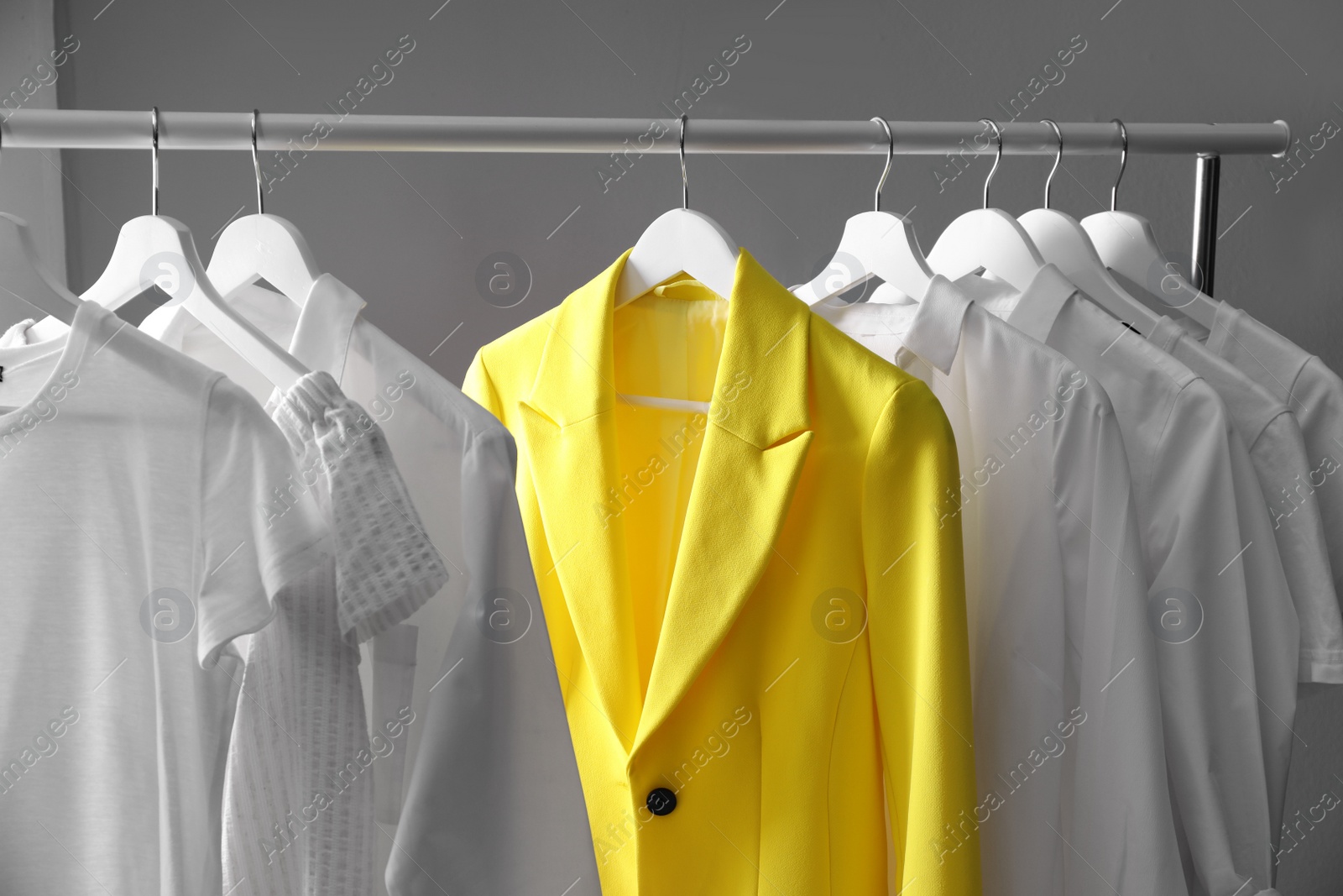 Yellow jacket hanging on rack among other clothes. Diversity concept Photo of Yellow jacket hanging on rack among other clothes. Diversity concept