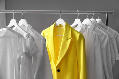 Yellow jacket hanging on rack among other clothes. Diversity concept Photo of Yellow jacket hanging on rack among other clothes. Diversity concept