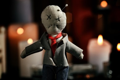 Photo of Voodoo doll pierced with pins in dark room, closeup. Curse ceremony