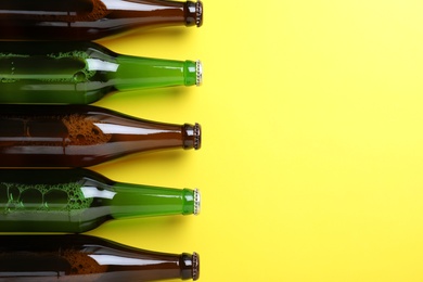 Bottles of beer on yellow background, flat lay. Space for text Photo of Bottles of beer on yellow background, flat lay. Space for text