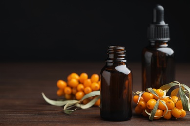 Natural sea buckthorn oil and fresh berries on wooden table. Space for text Photo of Natural sea buckthorn oil and fresh berries on wooden table. Space for text