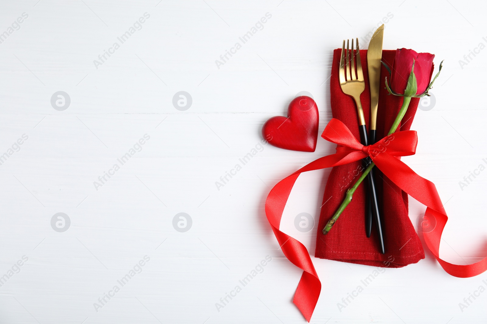 Top view of cutlery with napkin and decorative heart on white wooden table, space for text. Valentine's Day romantic dinner Photo of Top view of cutlery with napkin and decorative heart on white wooden table, space for text. Valentine's Day romantic dinner