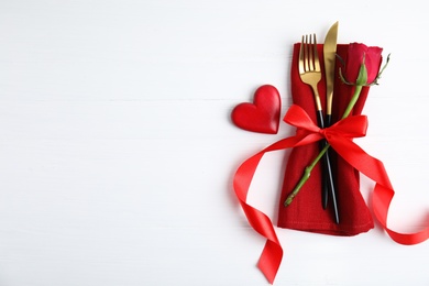 Top view of cutlery with napkin and decorative heart on white wooden table, space for text. Valentine's Day romantic dinner Photo of Top view of cutlery with napkin and decorative heart on white wooden table, space for text. Valentine's Day romantic dinner