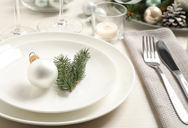 Festive table setting with beautiful dishware and Christmas decor on white wooden background Photo of Festive table setting with beautiful dishware and Christmas decor on white wooden background