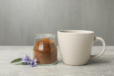 Jar with chicory powder, cup and flowers on light grey table Photo of Jar with chicory powder, cup and flowers on light grey table