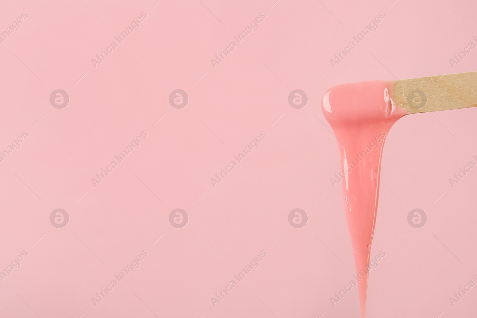 Wooden spatula with hot depilatory wax on pink background. Space for text Photo of Wooden spatula with hot depilatory wax on pink background. Space for text