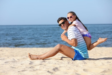Father and daughter on sandy beach near sea. Summer holidays with family Photo of Father and daughter on sandy beach near sea. Summer holidays with family