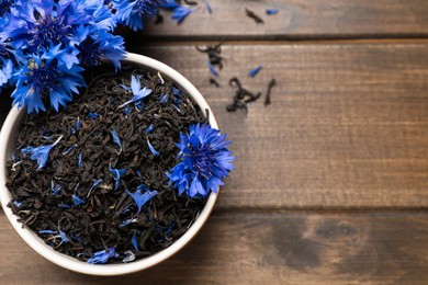 Bowl with dry tea leaves and cornflowers on wooden table, flat lay. Space for text Photo of Bowl with dry tea leaves and cornflowers on wooden table, flat lay. Space for text