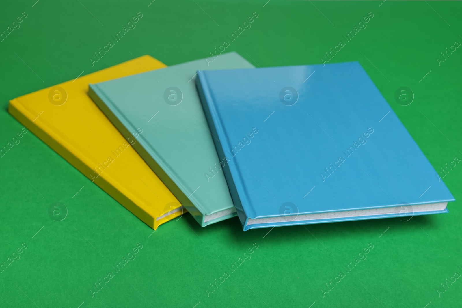 Stylish colorful planners on green background, closeup Photo of Stylish colorful planners on green background, closeup