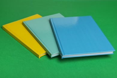 Stylish colorful planners on green background, closeup Photo of Stylish colorful planners on green background, closeup
