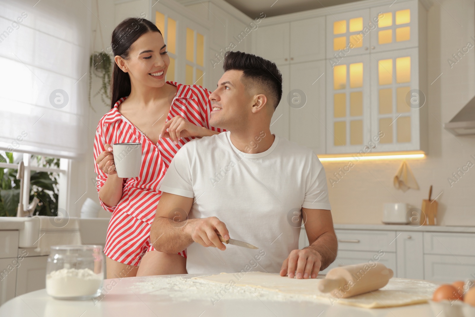 Happy couple wearing pyjamas and cooking together in kitchen Photo of Happy couple wearing pyjamas and cooking together in kitchen