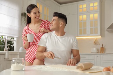Happy couple wearing pyjamas and cooking together in kitchen Photo of Happy couple wearing pyjamas and cooking together in kitchen