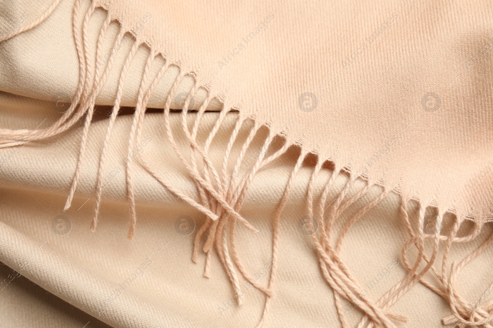 Photo of Beige soft cashmere scarf as background, closeup