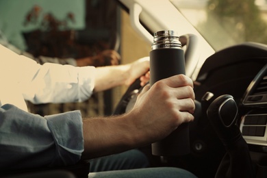 Man with thermos driving car, closeup view Photo of Man with thermos driving car, closeup view