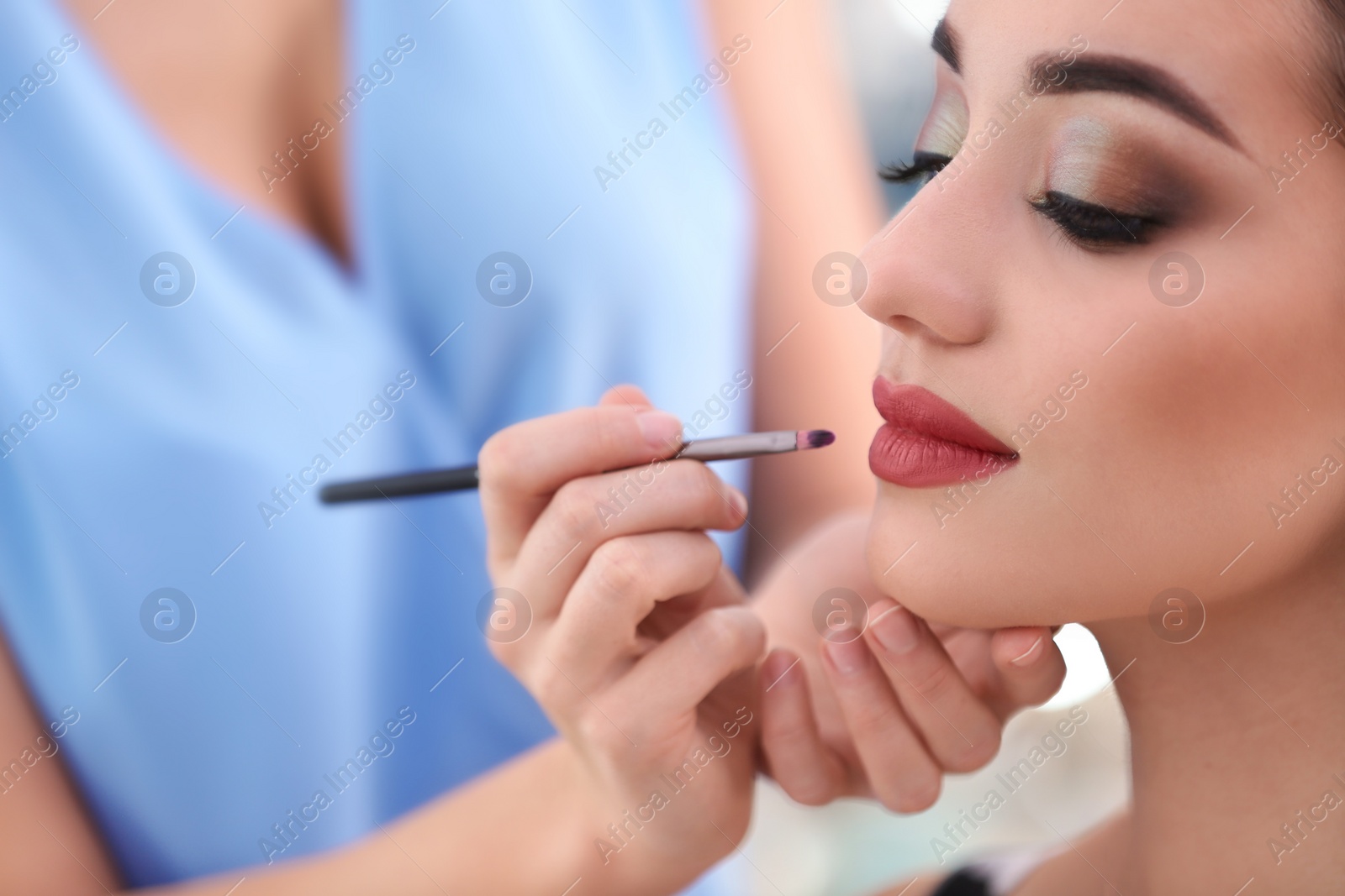 Professional visage artist applying makeup on woman's face in salon, closeup Photo of Professional visage artist applying makeup on woman's face in salon, closeup