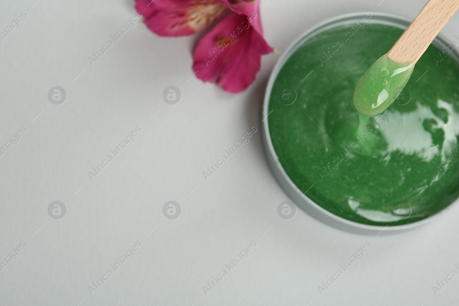 Wooden spatula and hot depilatory wax on light grey background, top view. Space for text Photo of Wooden spatula and hot depilatory wax on light grey background, top view. Space for text