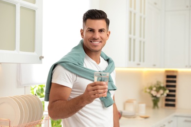 Man holding glass of pure water in kitchen Photo of Man holding glass of pure water in kitchen