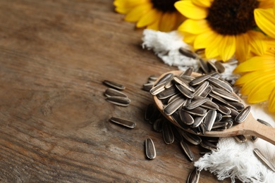 Organic sunflower seeds and flowers on wooden table, closeup. Space for text Photo of Organic sunflower seeds and flowers on wooden table, closeup. Space for text
