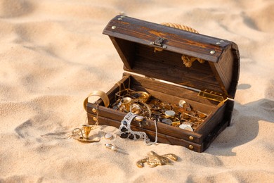 Open wooden treasure chest on sand outdoors Photo of Open wooden treasure chest on sand outdoors