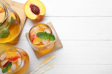 Delicious peach lemonade made with soda water on white wooden table, flat lay. Space for text Photo of Delicious peach lemonade made with soda water on white wooden table, flat lay. Space for text