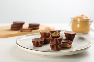 Cut and whole delicious peanut butter cups on white table Photo of Cut and whole delicious peanut butter cups on white table