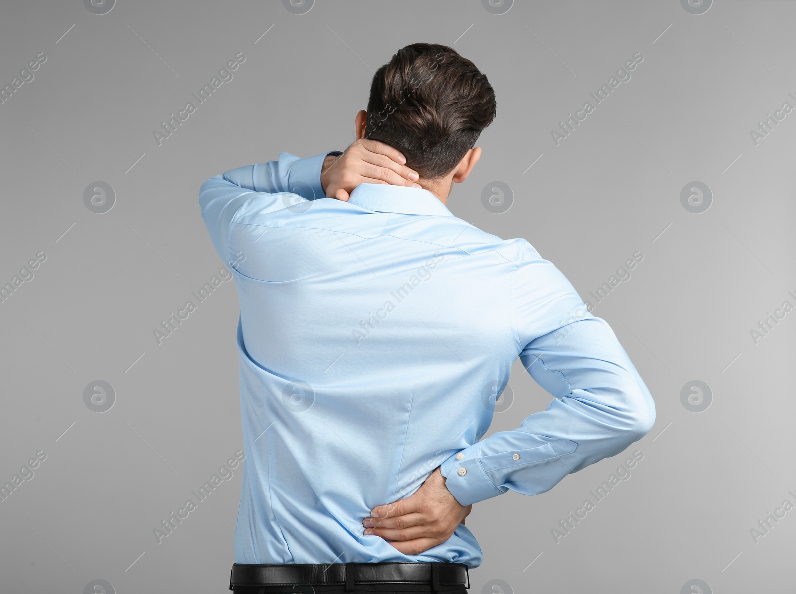 Young man suffering from neck pain on grey background Photo of Young man suffering from neck pain on grey background