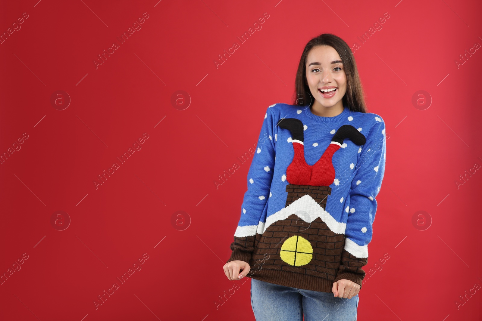 Young woman in Christmas sweater on red background, space for text Photo of Young woman in Christmas sweater on red background, space for text