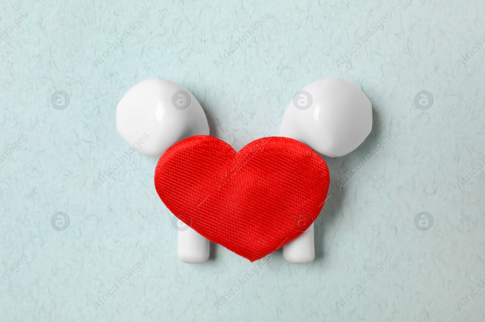 Modern earphones and red heart on turquoise background, flat lay. Listening love music songs Photo of Modern earphones and red heart on turquoise background, flat lay. Listening love music songs