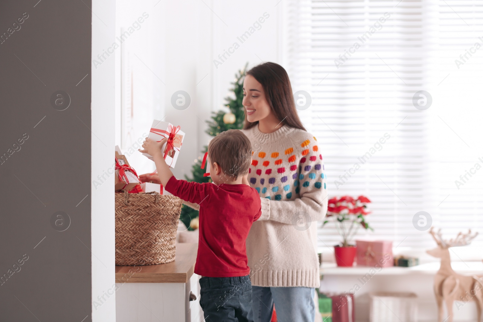 Mother and son with Christmas gifts at home. Advent calendar in basket Photo of Mother and son with Christmas gifts at home. Advent calendar in basket