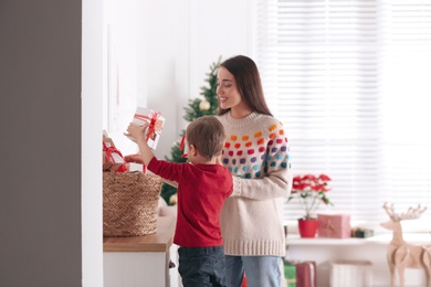 Mother and son with Christmas gifts at home. Advent calendar in basket Photo of Mother and son with Christmas gifts at home. Advent calendar in basket