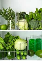 Different green vegetables and fruits on shelves of refrigerator Photo of Different green vegetables and fruits on shelves of refrigerator