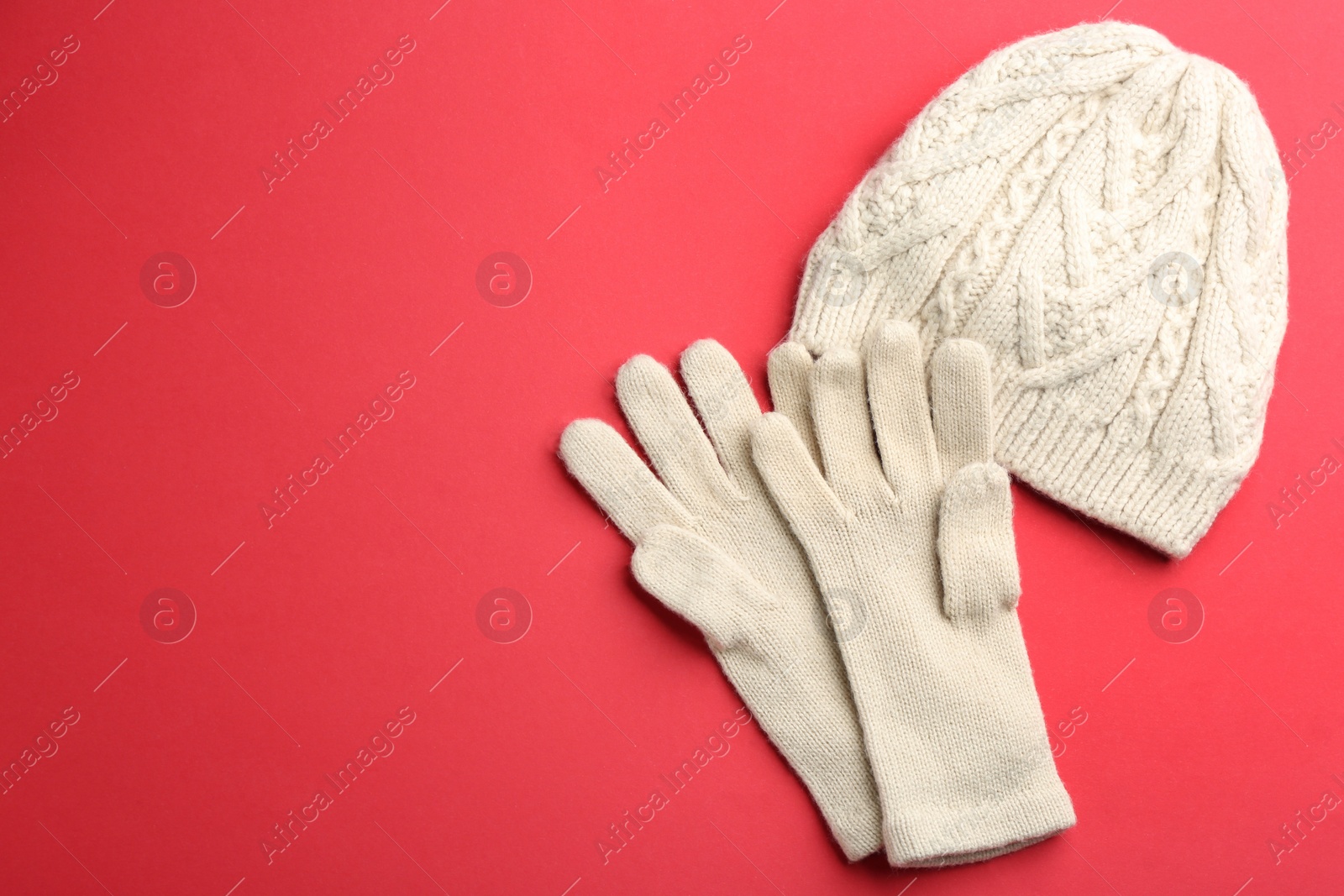 Woolen gloves and hat on red background, flat lay. Space for text Photo of Woolen gloves and hat on red background, flat lay. Space for text