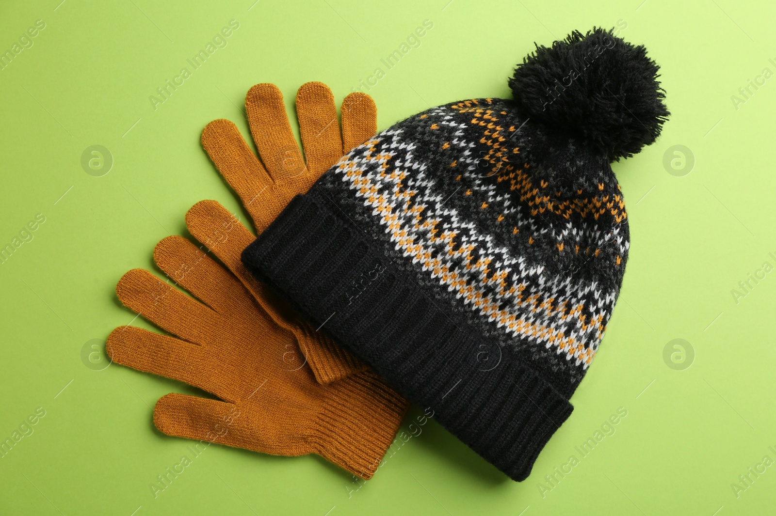 Woolen gloves and hat on green background, flat lay Photo of Woolen gloves and hat on green background, flat lay