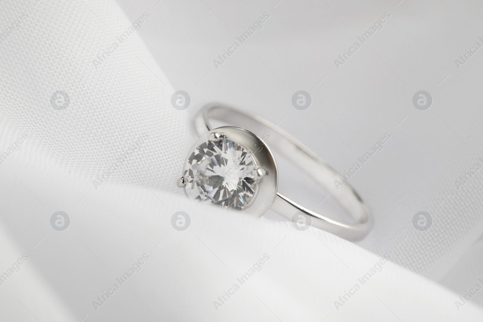 Beautiful engagement ring on white fabric, closeup Photo of Beautiful engagement ring on white fabric, closeup