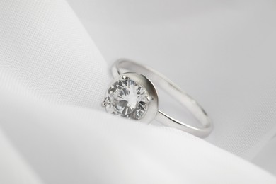 Beautiful engagement ring on white fabric, closeup Photo of Beautiful engagement ring on white fabric, closeup