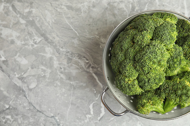 Fresh green broccoli in colander on grey marble table, top view. Space for text Photo of Fresh green broccoli in colander on grey marble table, top view. Space for text