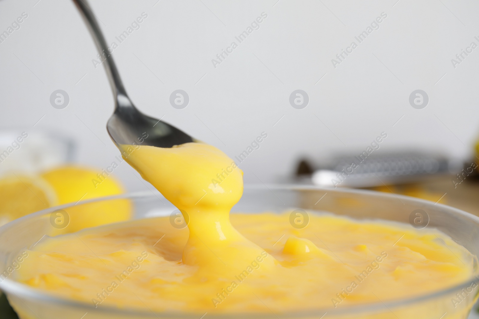Spoon with delicious lemon curd above bowl, closeup Photo of Spoon with delicious lemon curd above bowl, closeup