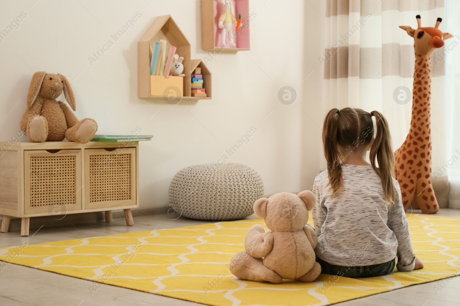Lonely little girl with teddy bear sitting on floor at home, back view. Autism concept Photo of Lonely little girl with teddy bear sitting on floor at home, back view. Autism concept