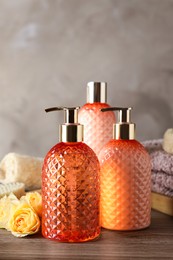 Stylish dispensers with liquid soap and other bathroom amenities on wooden table Photo of Stylish dispensers with liquid soap and other bathroom amenities on wooden table