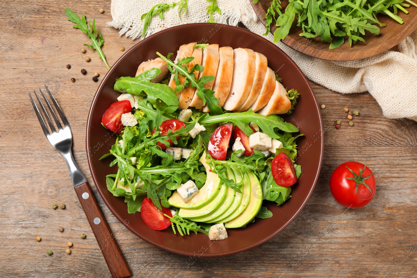 Delicious salad with chicken, arugula and avocado on wooden table, flat lay Photo of Delicious salad with chicken, arugula and avocado on wooden table, flat lay