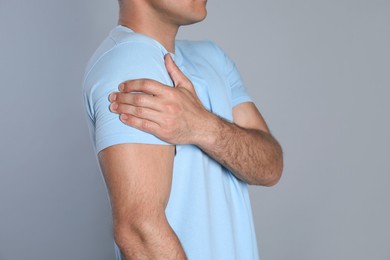 Man suffering from shoulder pain on grey background, closeup Photo of Man suffering from shoulder pain on grey background, closeup