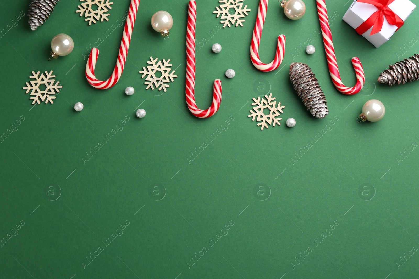 Flat lay composition with candy canes and Christmas decor on green background. Space for text Photo of Flat lay composition with candy canes and Christmas decor on green background. Space for text
