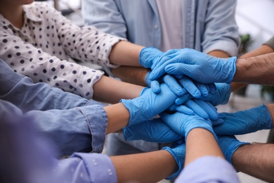Group of people in blue medical gloves stacking hands indoors, closeup Photo of Group of people in blue medical gloves stacking hands indoors, closeup
